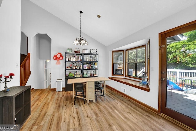 dining space featuring light wood finished floors, plenty of natural light, an inviting chandelier, and stairs
