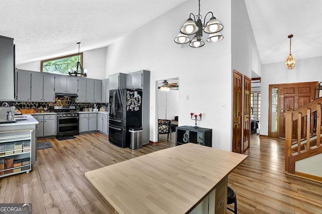 kitchen with range with two ovens, backsplash, gray cabinetry, high vaulted ceiling, and refrigerator with ice dispenser