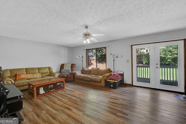 living room featuring a ceiling fan, wood finished floors, and a textured ceiling