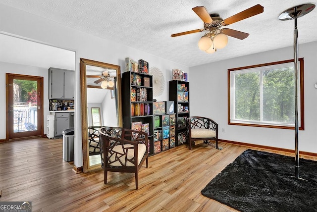 sitting room with light wood finished floors, plenty of natural light, a ceiling fan, and a textured ceiling