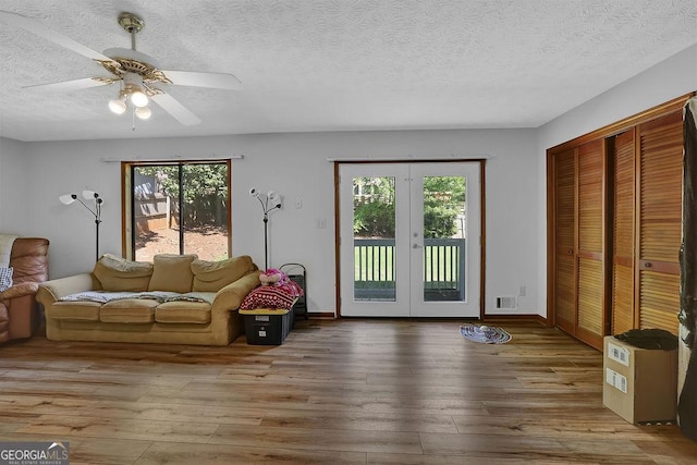 living area featuring wood-type flooring, ceiling fan, visible vents, and plenty of natural light