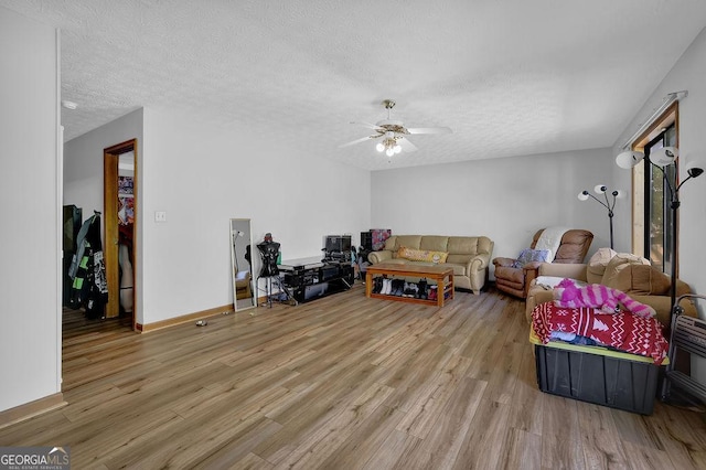 living area with wood finished floors, a textured ceiling, a ceiling fan, and baseboards