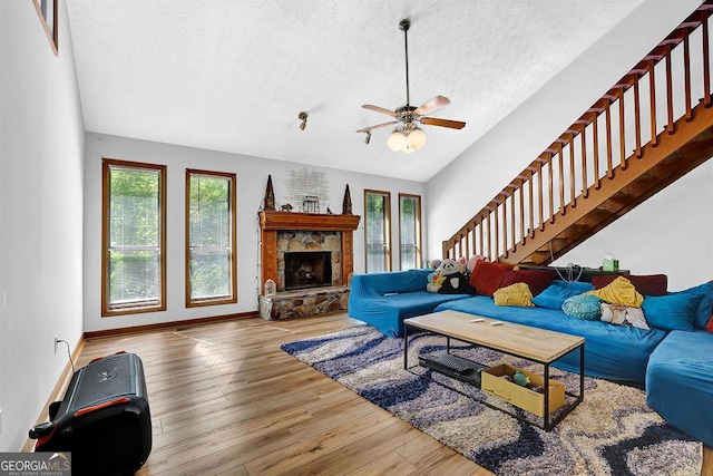 living room featuring vaulted ceiling, a textured ceiling, stairs, and wood finished floors