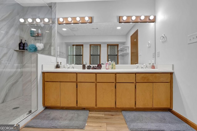 bathroom with a shower stall, a sink, and double vanity