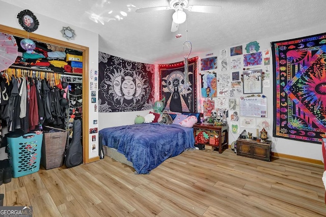 bedroom with a textured ceiling, baseboards, a ceiling fan, wood finished floors, and a closet