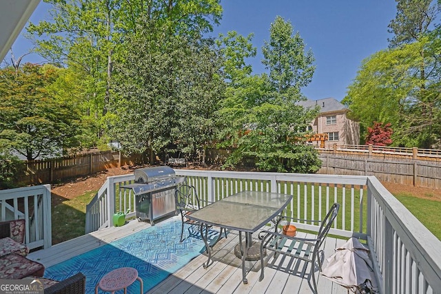 deck featuring a grill, a fenced backyard, a yard, and outdoor dining space
