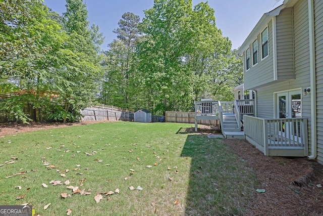 view of yard with a fenced backyard, a deck, an outbuilding, and a shed