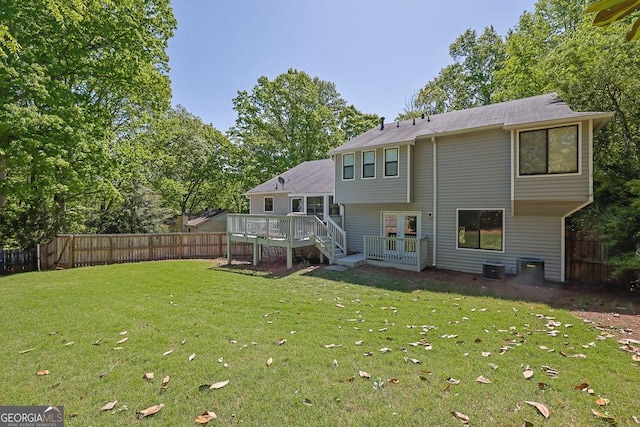 rear view of house featuring a wooden deck, french doors, a lawn, and a fenced backyard