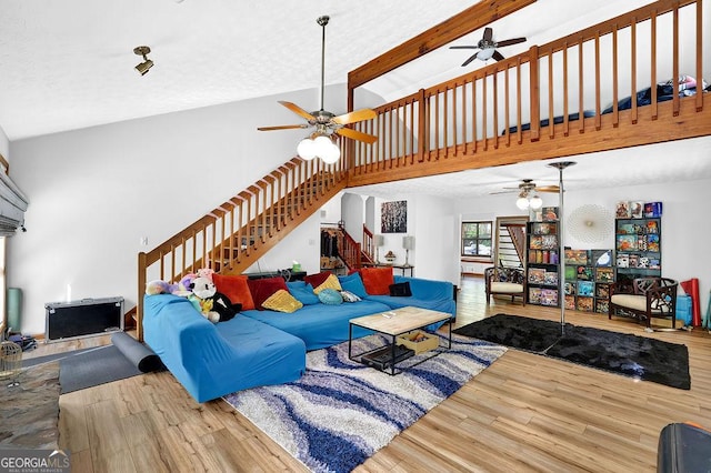 living room with stairway, a high ceiling, a ceiling fan, and wood finished floors