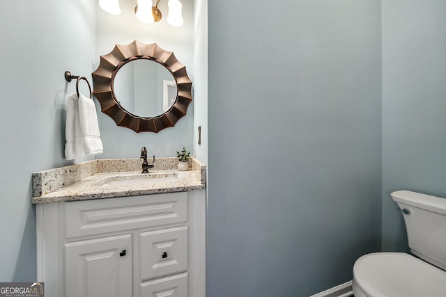 half bathroom with baseboards, toilet, and vanity