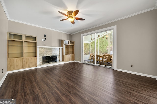 unfurnished living room with dark wood-style floors, crown molding, a premium fireplace, and a ceiling fan