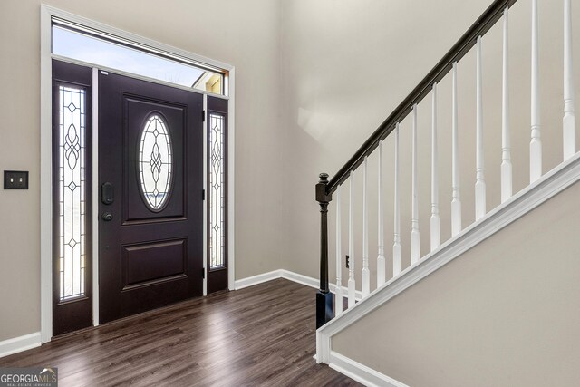entrance foyer featuring stairs, baseboards, and dark wood-style flooring