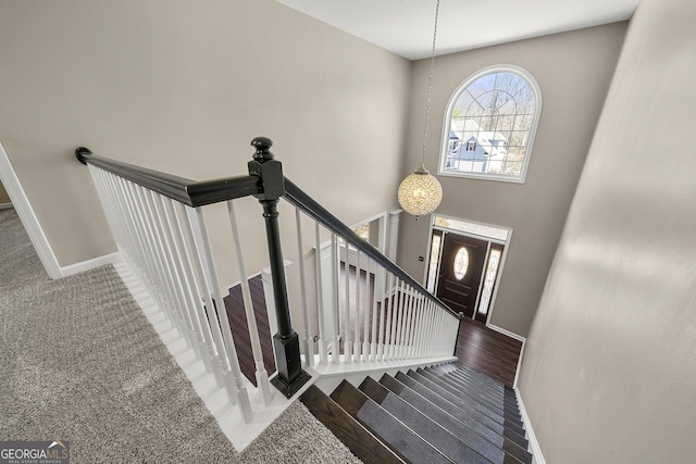 stairs with baseboards, a high ceiling, and wood finished floors