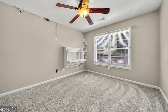 carpeted spare room featuring baseboards, ceiling fan, and visible vents