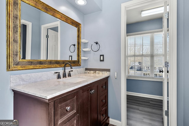 bathroom with baseboards, wood finished floors, and vanity