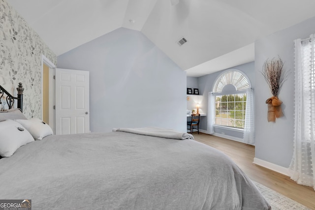 bedroom featuring wood finished floors, baseboards, lofted ceiling, and visible vents