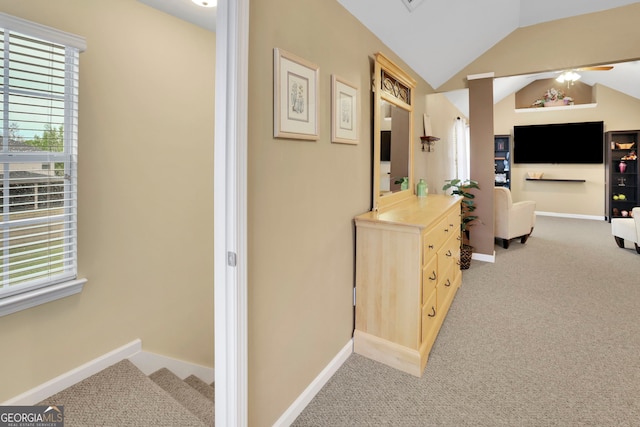 hallway with baseboards, stairs, light colored carpet, and lofted ceiling