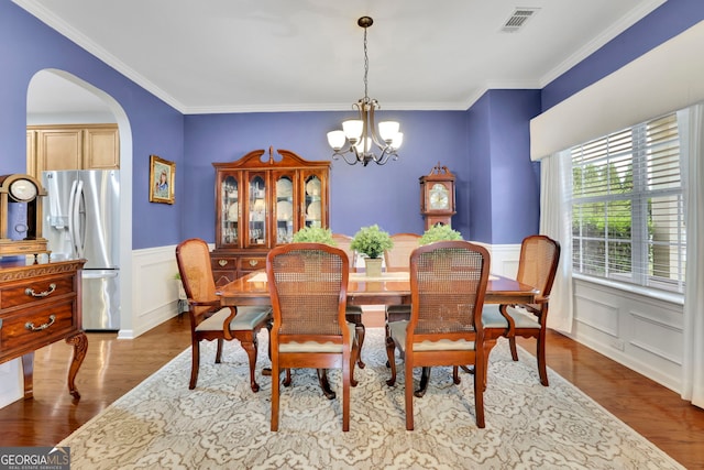 dining space featuring a notable chandelier, dark wood-style flooring, a wainscoted wall, visible vents, and arched walkways