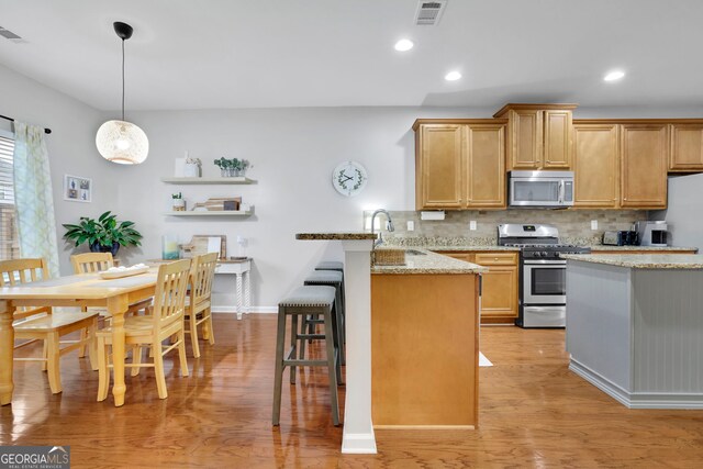 kitchen featuring a peninsula, visible vents, appliances with stainless steel finishes, a sink, and backsplash