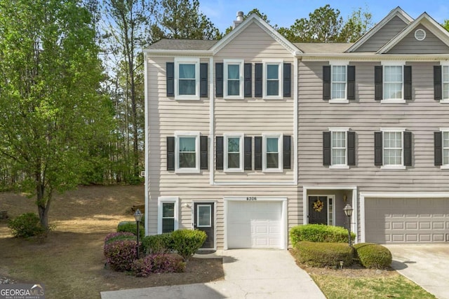 multi unit property featuring an attached garage, a chimney, and driveway
