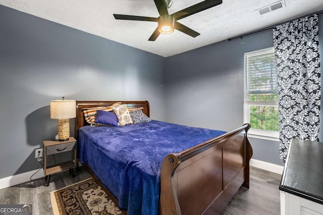bedroom with visible vents, baseboards, a ceiling fan, a textured ceiling, and wood finished floors