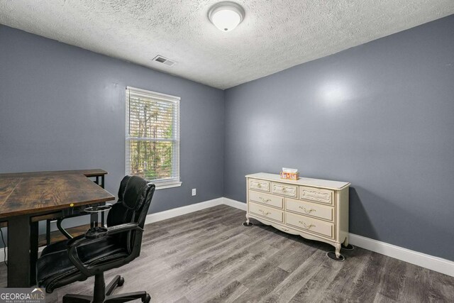 office space with a textured ceiling, wood finished floors, baseboards, and visible vents