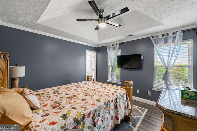 bedroom with dark wood-style floors, a textured ceiling, visible vents, multiple windows, and a tray ceiling