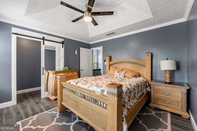 bedroom featuring a barn door, visible vents, dark wood-style flooring, and a raised ceiling