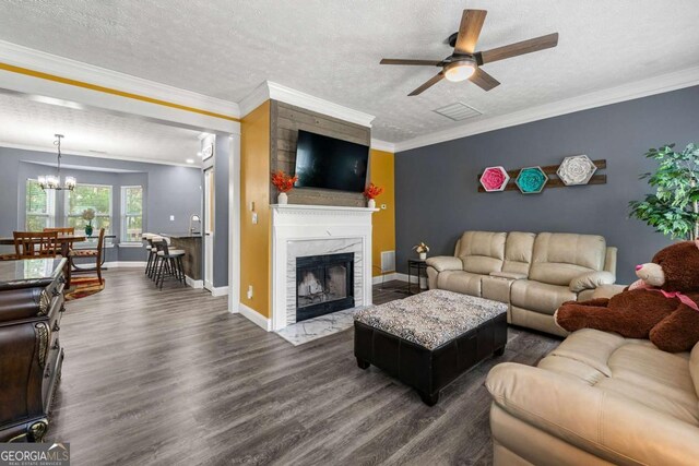 living room with a textured ceiling, ceiling fan with notable chandelier, ornamental molding, and dark wood-style floors