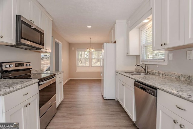 477 Victoria Rd, Woodstock, GA 30189 - kitchen with stainless steel appliances, a chandelier, light wood-style flooring, white cabinets, and recessed lighting