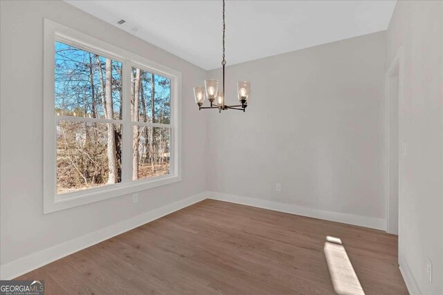 4444 Sullivan Rd, Powder Springs, GA 30127 - unfurnished dining area with an inviting chandelier, wood finished floors, and a wealth of natural light