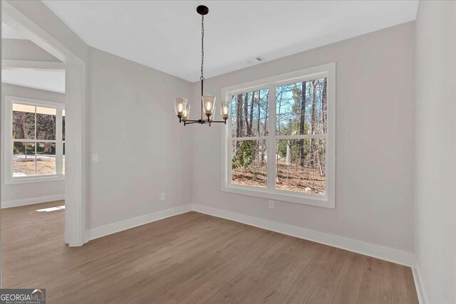 4444 Sullivan Rd, Powder Springs, GA 30127 - unfurnished dining area featuring a wealth of natural light, a notable chandelier, wood finished floors, and baseboards
