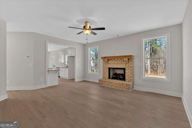 4444 Sullivan Rd, Powder Springs, GA 30127 - unfurnished living room with baseboards, ceiling fan, light wood-style flooring, and a fireplace