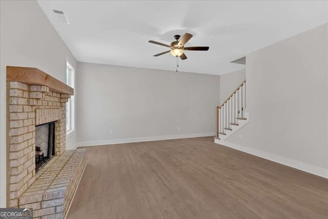 4444 Sullivan Rd, Powder Springs, GA 30127 - unfurnished living room with a brick fireplace, stairs, baseboards, a ceiling fan, and wood finished floors