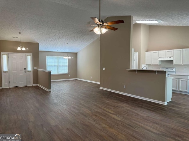 unfurnished living room with a textured ceiling, high vaulted ceiling, baseboards, dark wood finished floors, and ceiling fan with notable chandelier