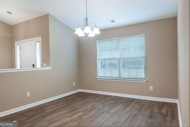 unfurnished room with a textured ceiling, visible vents, baseboards, wood finished floors, and an inviting chandelier