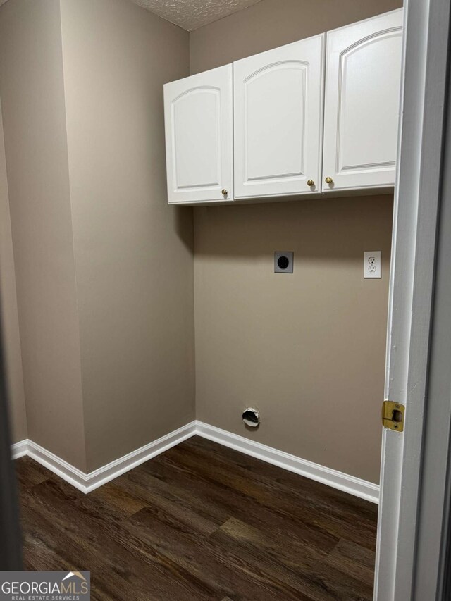 washroom with a textured ceiling, baseboards, dark wood finished floors, electric dryer hookup, and cabinet space
