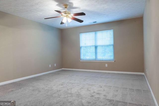 carpeted empty room with baseboards, visible vents, a textured ceiling, and a ceiling fan