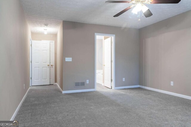 carpeted empty room with baseboards, visible vents, ceiling fan, and a textured ceiling