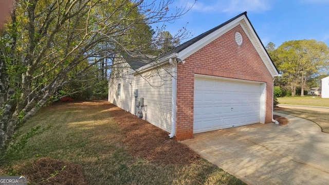 view of property exterior featuring brick siding, a garage, and a yard