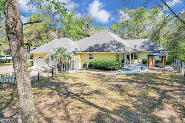 view of front facade featuring a gazebo, stucco siding, fence, and a garage