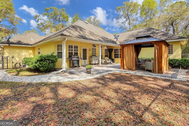 rear view of property with stucco siding, an outdoor hangout area, a gazebo, and a patio area