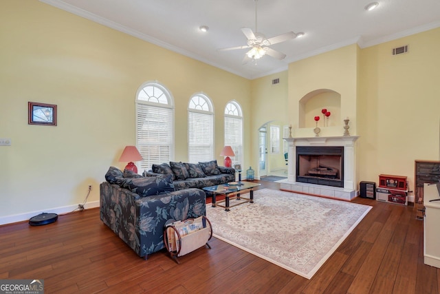 living area featuring baseboards, visible vents, ceiling fan, ornamental molding, and dark wood-style flooring