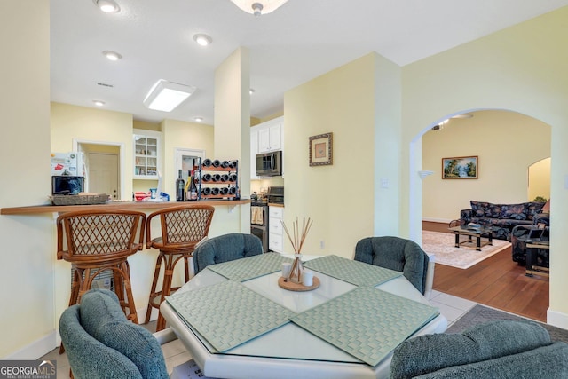dining area featuring tile patterned floors, arched walkways, baseboards, and recessed lighting