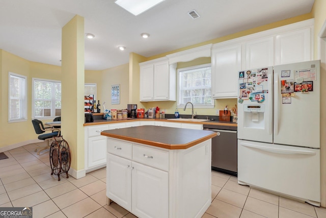 kitchen with light tile patterned floors, a sink, visible vents, dishwasher, and white fridge with ice dispenser