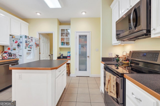 kitchen featuring white cabinets, light tile patterned flooring, dark countertops, and appliances with stainless steel finishes