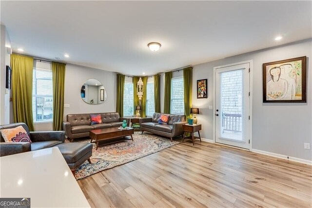 living area featuring baseboards, light wood-style floors, and recessed lighting