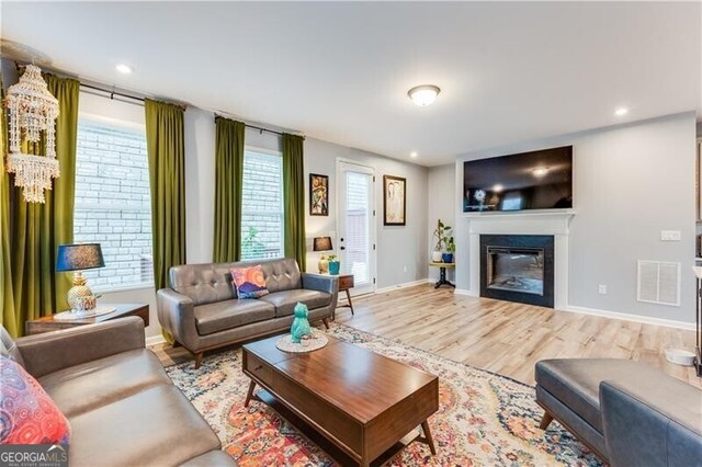 living room featuring recessed lighting, visible vents, wood finished floors, and a glass covered fireplace
