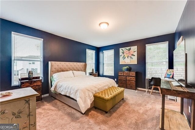 bedroom with baseboards, multiple windows, and light colored carpet