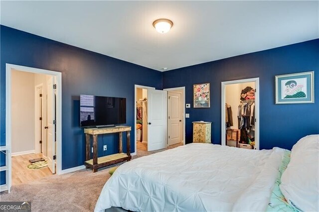 bedroom featuring a closet, baseboards, connected bathroom, carpet floors, and a spacious closet